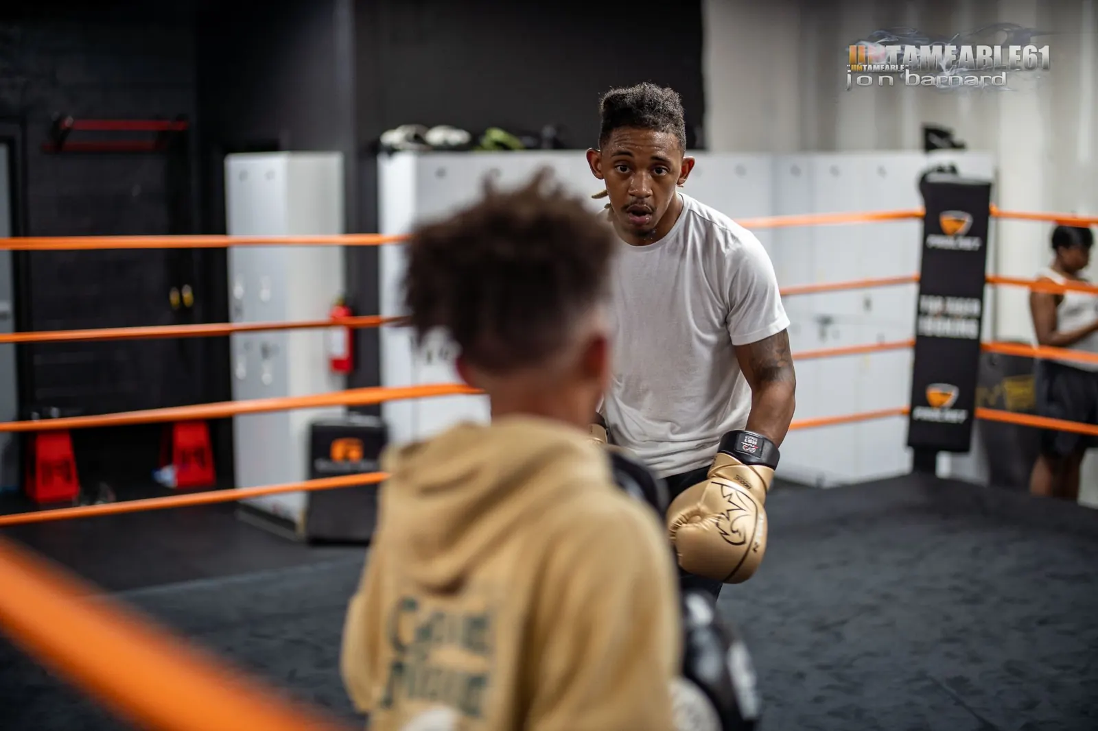 A Top Tiger coach in gold gloves working one-on-one with a young boxer